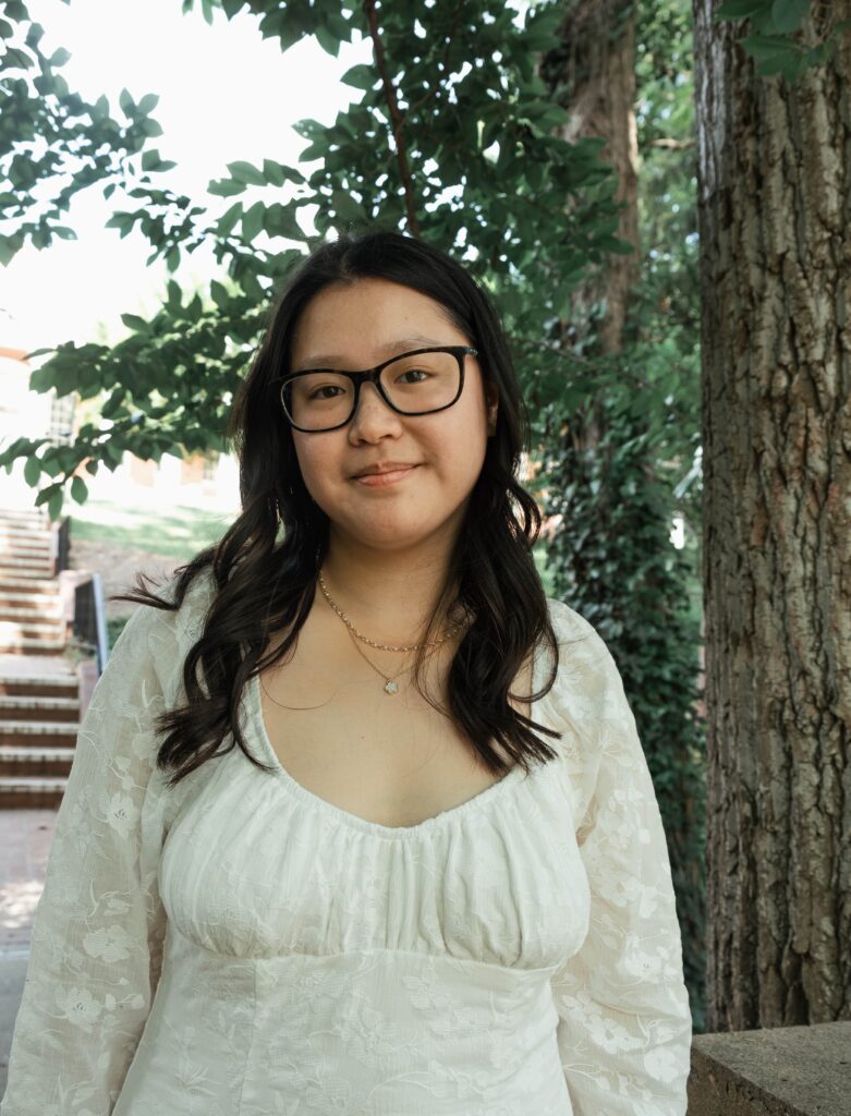 Anna Blake standing outside in a white dress smiling