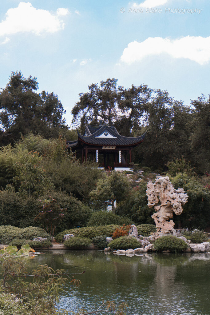 Portrait of Chinese house on a hilltop with a rock statue at the base of the hill